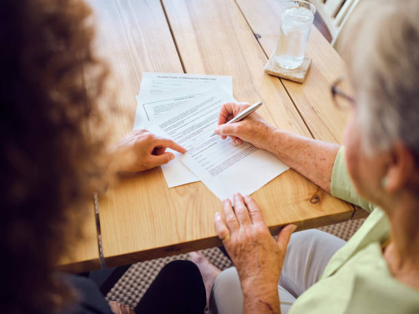 Bakersfield Living Trust Attorney - A senior aged woman signing documents with a financial adviser in her home.