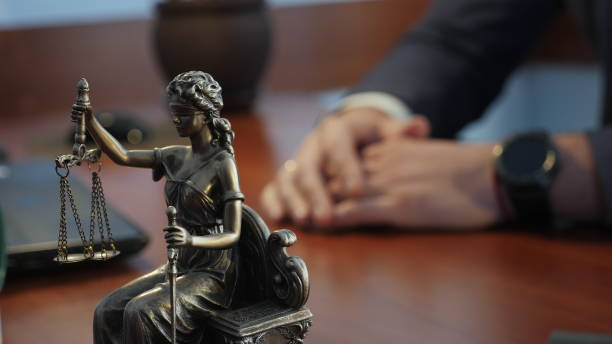Criminal Defense Attorney - Statue of justice on the table against the background of the hand gestures of a man, a lawyer or a judge