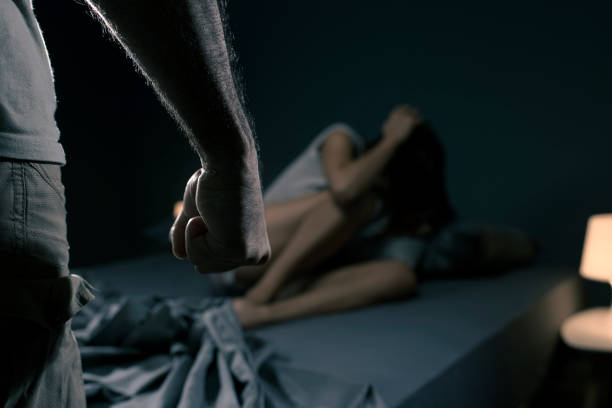 Domestic Violence Victims - Man threatening a woman in the bedroom, she is scared and lying in bed, domestic violence concept